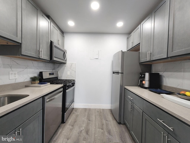 kitchen with gray cabinetry, light hardwood / wood-style flooring, and stainless steel appliances