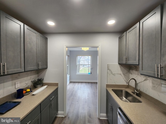 kitchen with stainless steel dishwasher, dark wood-type flooring, sink, and tasteful backsplash