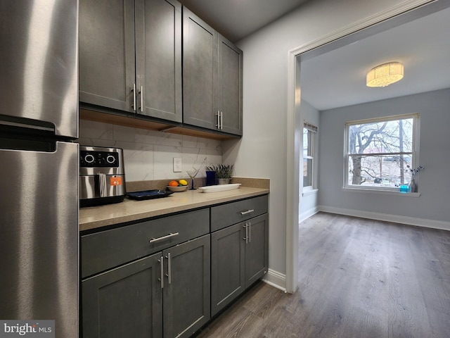 kitchen with backsplash, stainless steel refrigerator, gray cabinets, and dark wood-type flooring