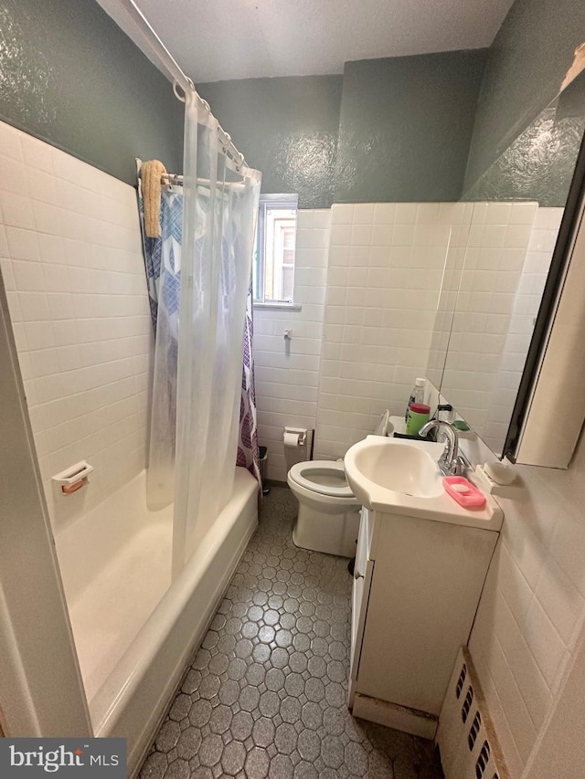 full bathroom featuring vanity, radiator, toilet, shower / bath combo with shower curtain, and tile walls