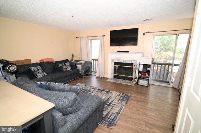 living room featuring a high end fireplace, a textured ceiling, and hardwood / wood-style flooring