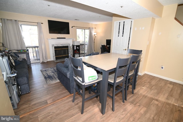 dining room with wood-type flooring, a premium fireplace, and a textured ceiling