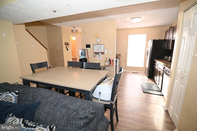 dining room with a textured ceiling and light hardwood / wood-style flooring