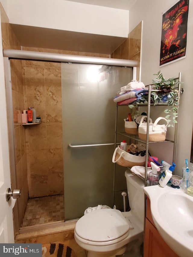 bathroom featuring vanity, toilet, and a shower with shower door