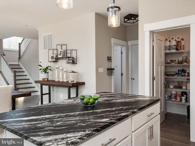 kitchen with dark stone countertops, white cabinetry, dark hardwood / wood-style flooring, and decorative light fixtures