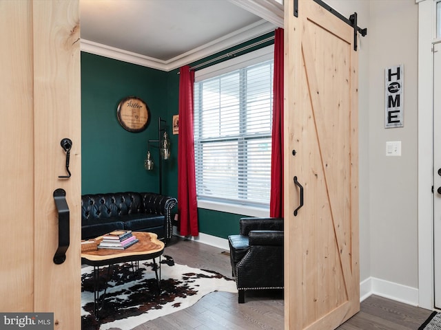 sitting room with a barn door, ornamental molding, a healthy amount of sunlight, and hardwood / wood-style flooring