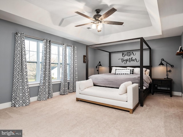 carpeted bedroom featuring a tray ceiling and ceiling fan