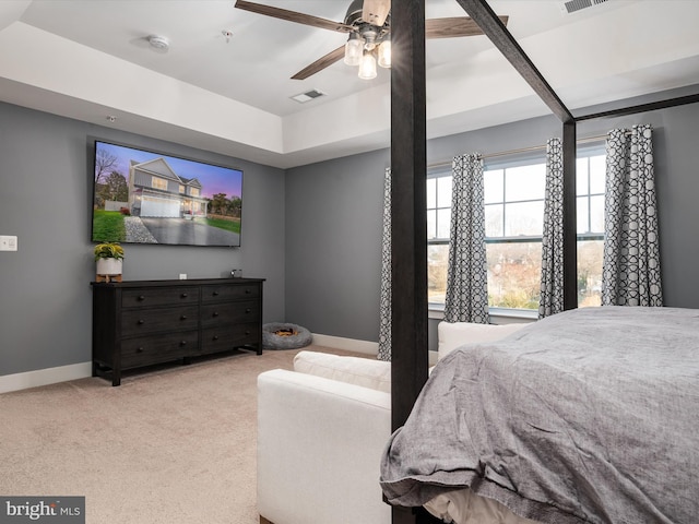 carpeted bedroom with a raised ceiling and ceiling fan