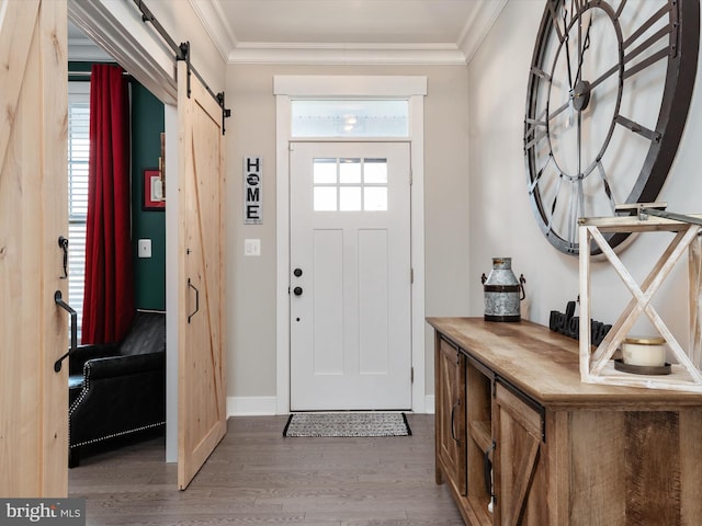 entrance foyer with hardwood / wood-style floors, plenty of natural light, a barn door, and crown molding