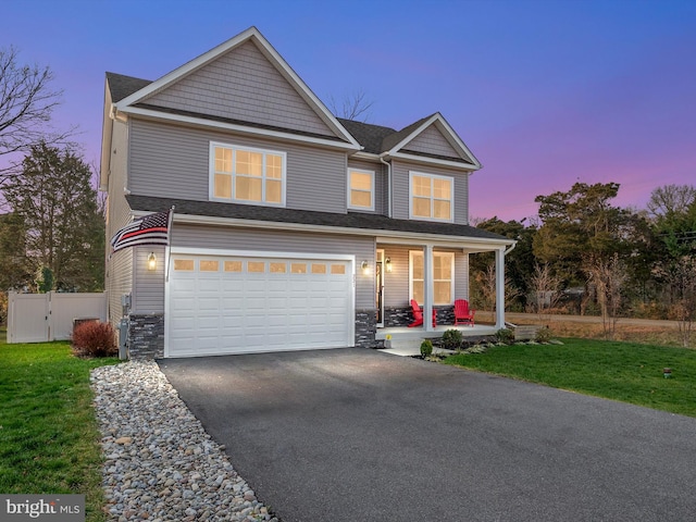 view of front of house featuring covered porch, a garage, and a lawn