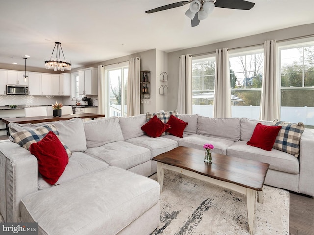 living room featuring ceiling fan with notable chandelier and light hardwood / wood-style floors