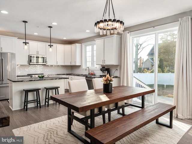 dining space featuring a chandelier, plenty of natural light, dark wood-type flooring, and sink