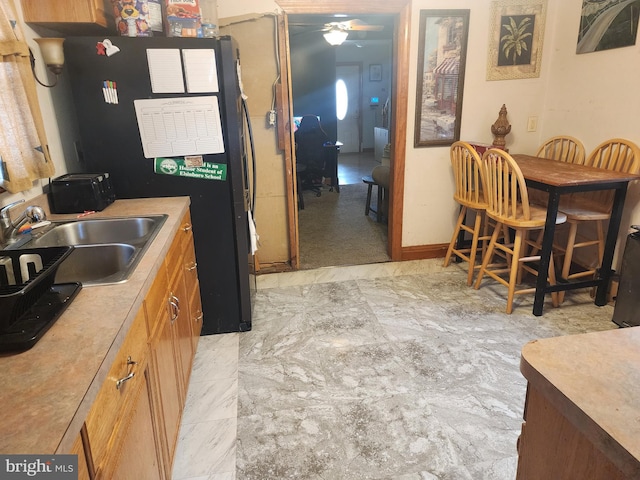 kitchen featuring ceiling fan, black fridge, and sink