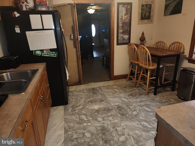 kitchen featuring ceiling fan, black fridge, and sink