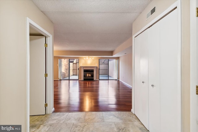 hallway featuring light hardwood / wood-style floors and a textured ceiling