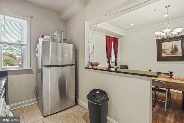 kitchen with kitchen peninsula, stainless steel fridge, crown molding, a chandelier, and light tile patterned flooring