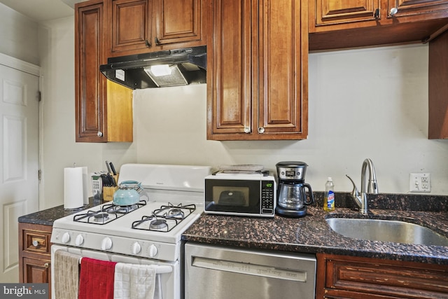 kitchen with dark stone countertops, stainless steel dishwasher, white gas stove, and sink