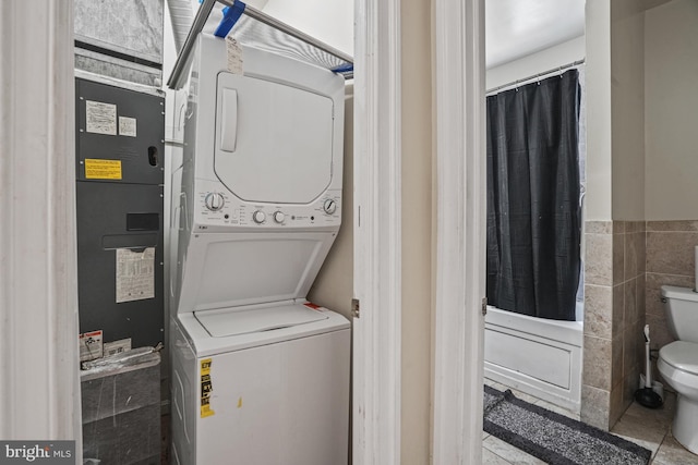 washroom featuring stacked washer / dryer and tile walls