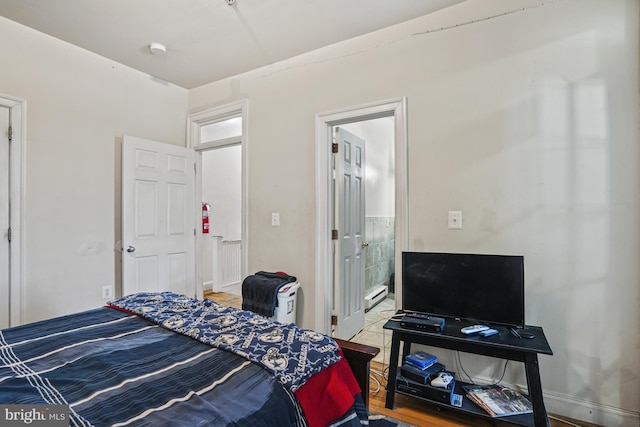 bedroom featuring connected bathroom and a baseboard heating unit