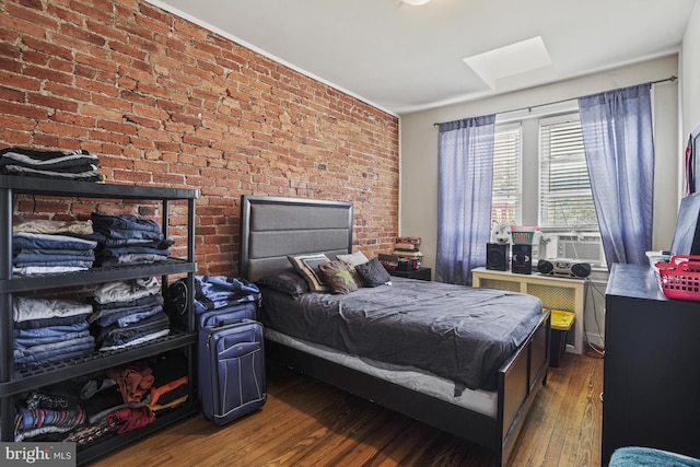 bedroom with cooling unit, dark hardwood / wood-style flooring, and brick wall