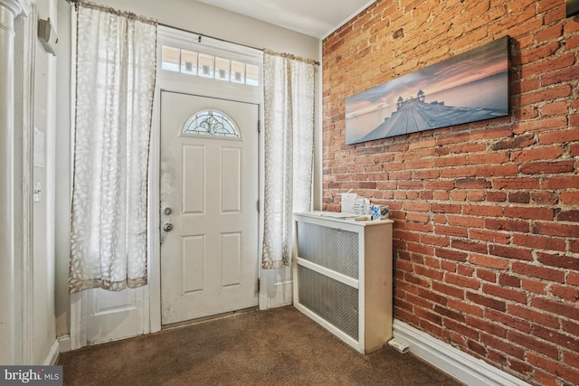 carpeted entrance foyer featuring brick wall