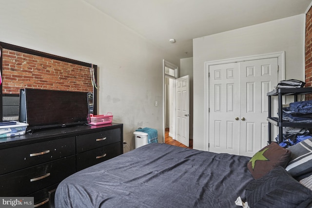 bedroom featuring a closet and brick wall