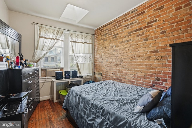 bedroom featuring dark hardwood / wood-style floors and brick wall