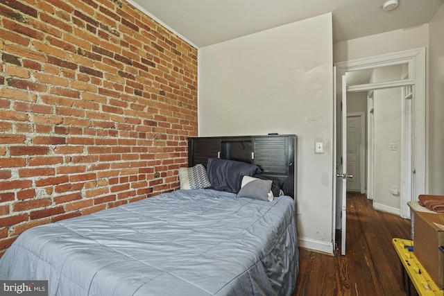 bedroom with a closet, brick wall, and dark hardwood / wood-style floors