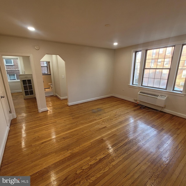 unfurnished room with a wall mounted AC and light hardwood / wood-style flooring