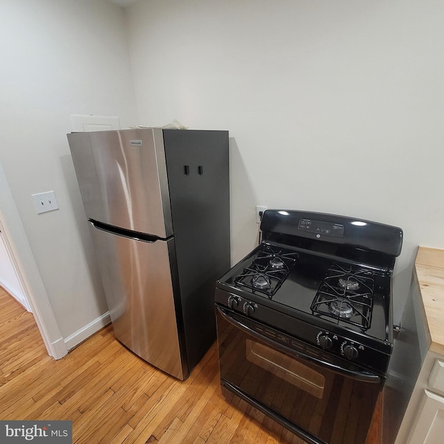 kitchen with gas stove, stainless steel fridge, and light hardwood / wood-style floors