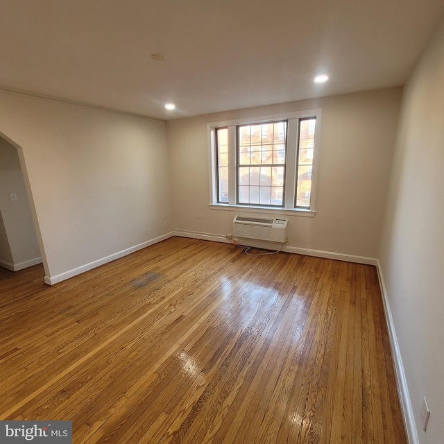 unfurnished room with an AC wall unit and light hardwood / wood-style flooring