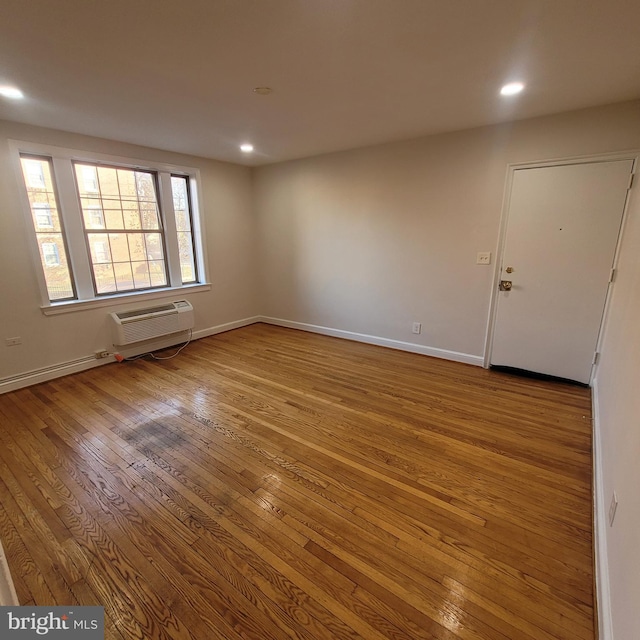 spare room featuring a wall unit AC and light wood-type flooring