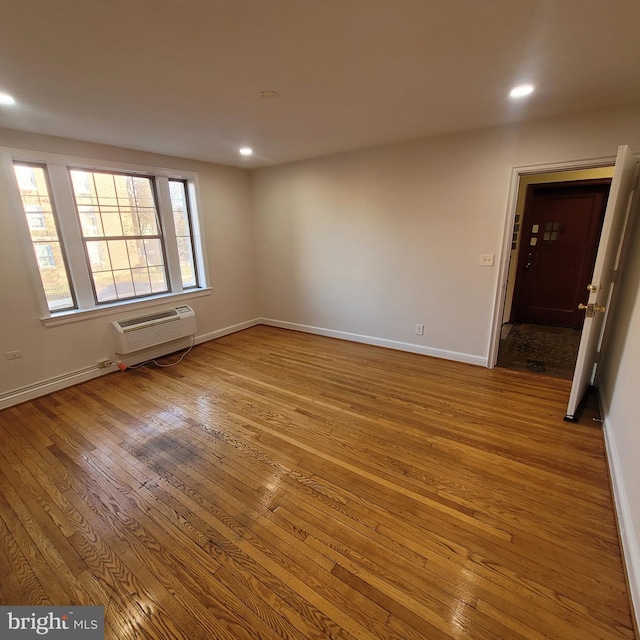 spare room with a wall mounted AC and light wood-type flooring