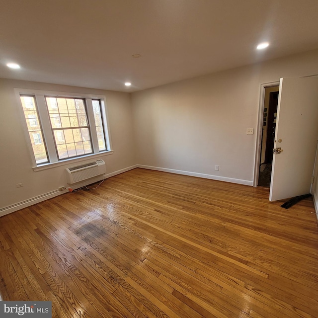 empty room featuring light hardwood / wood-style floors and an AC wall unit