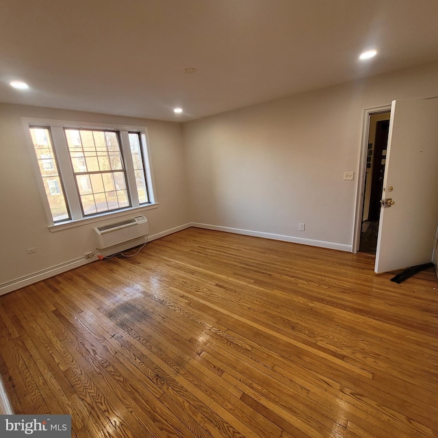 empty room with a wall unit AC and light hardwood / wood-style floors