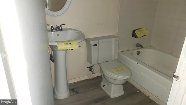 bathroom with hardwood / wood-style flooring, a bathtub, and toilet