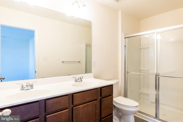 bathroom featuring vanity, toilet, and a shower with door