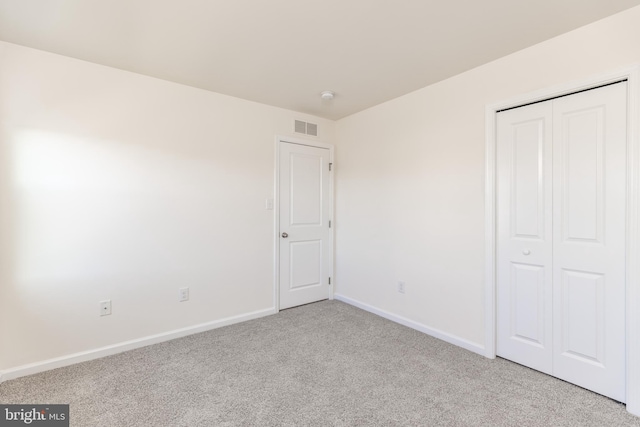 unfurnished bedroom with light carpet and a closet