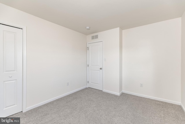 unfurnished bedroom featuring light carpet and a closet