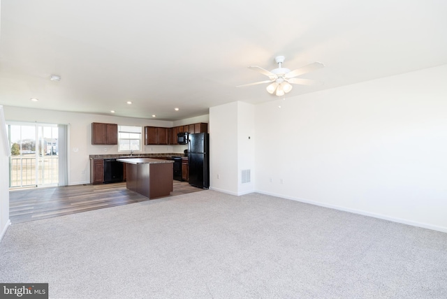 kitchen with a center island, light colored carpet, ceiling fan, and black appliances