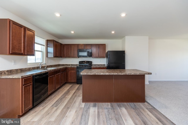 kitchen with sink, light carpet, a center island, and black appliances