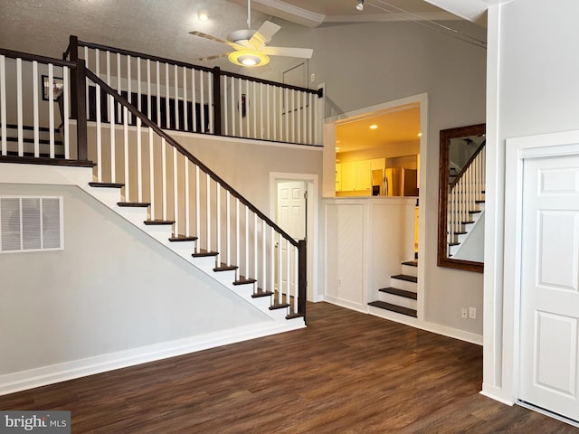 staircase with a high ceiling, ceiling fan, and hardwood / wood-style floors