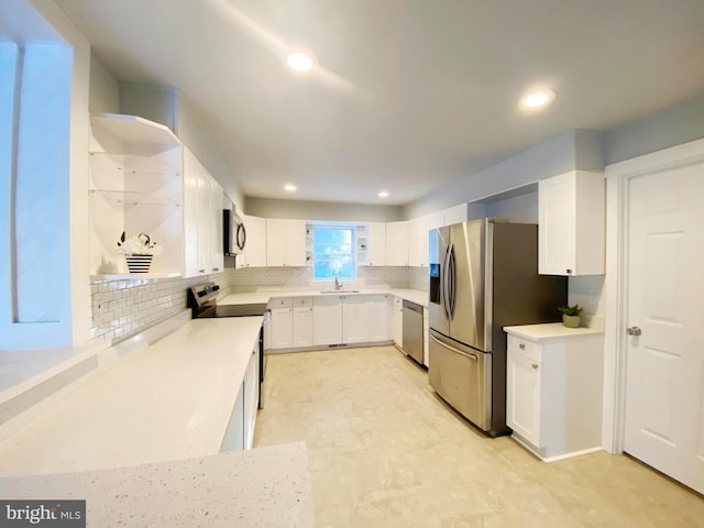 kitchen featuring appliances with stainless steel finishes, tasteful backsplash, white cabinets, and sink