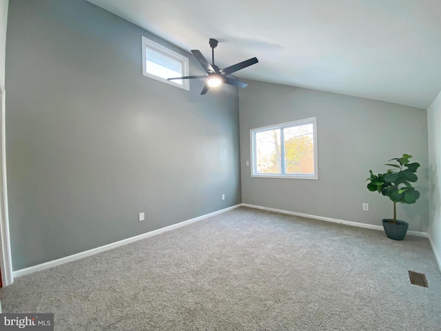 carpeted spare room with ceiling fan, vaulted ceiling, and plenty of natural light