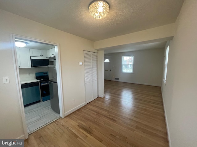 spare room with light hardwood / wood-style flooring and a textured ceiling