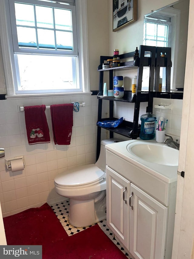 bathroom featuring toilet, vanity, tile patterned floors, and tile walls