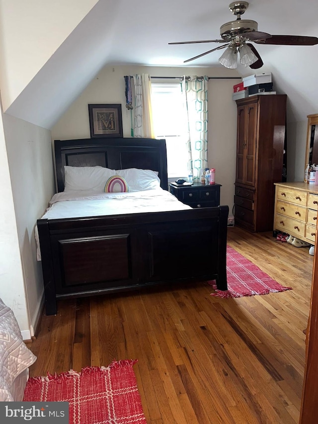 bedroom featuring dark hardwood / wood-style floors, vaulted ceiling, and ceiling fan