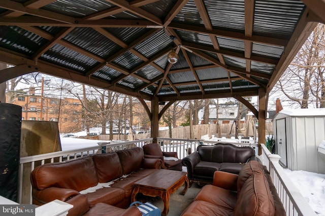 snow covered deck featuring a gazebo, an outdoor living space, and a storage unit