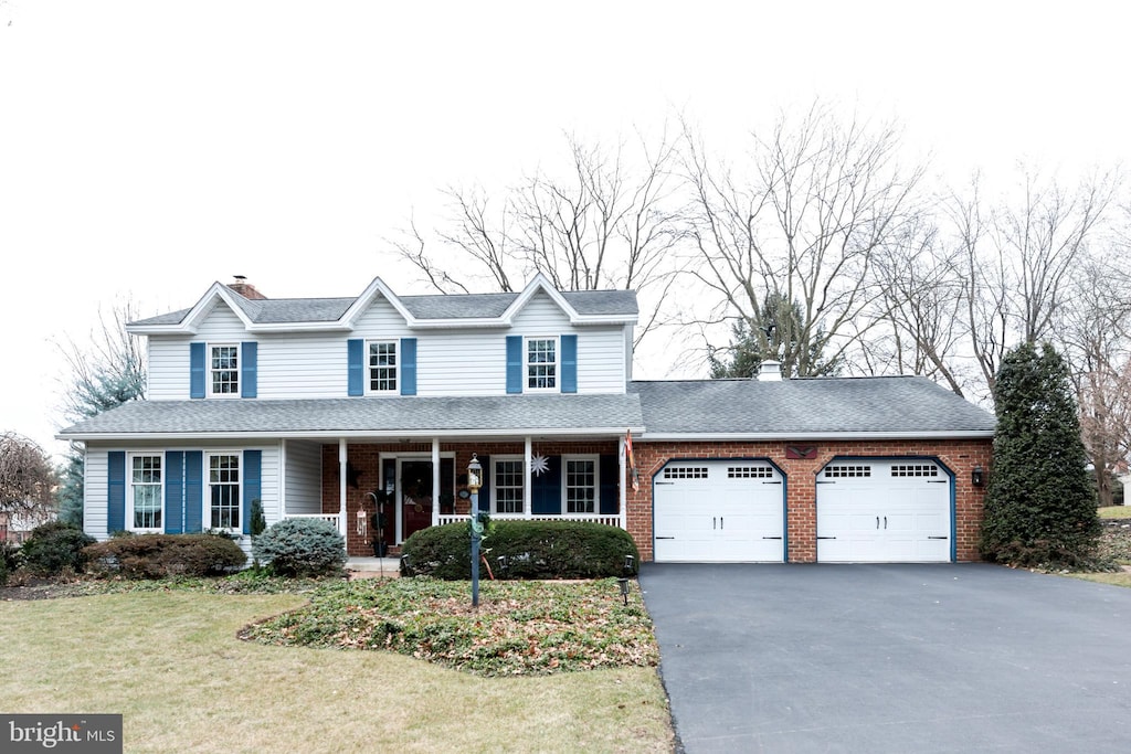 front of property featuring covered porch, a garage, and a front lawn