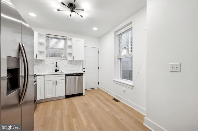 kitchen featuring sink, a healthy amount of sunlight, stainless steel appliances, decorative backsplash, and white cabinets